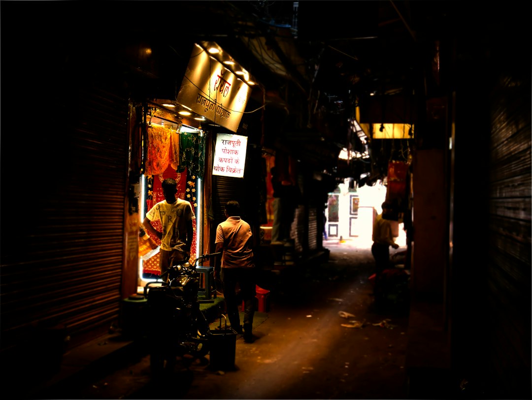 People walk through a dimly lit market alleyway with stalls