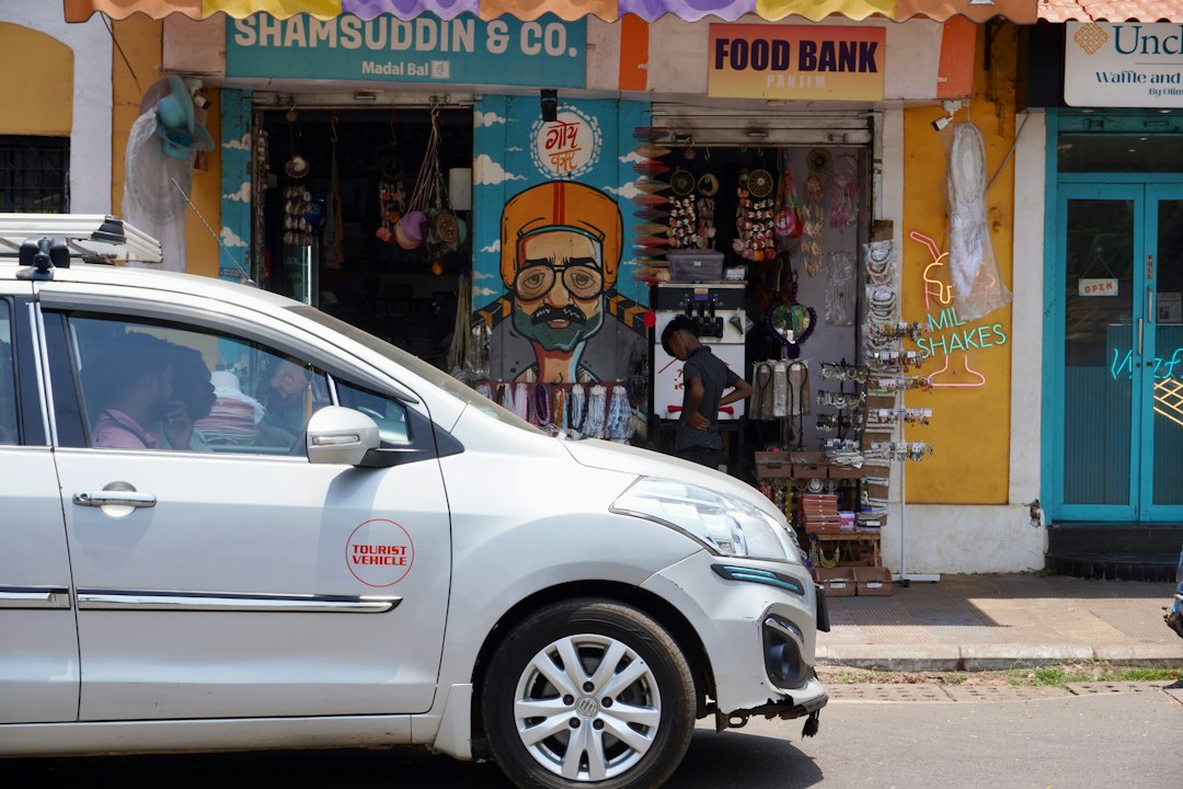 Silver car passes colorful storefront with mural
